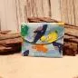 Preview: Kleiner handgenähter Geldbeutel von chic-peppig-bunt aus blauem Stoff mit Fisch-Motiv und bunt gestreiftem Innenfutter auf hellem Hintergrund.