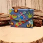 Preview: Kleiner handgenähter Geldbeutel von chic-peppig-bunt aus blauem Stoff mit Bienen-Motiv und grün gepunktetem Innenfutter auf hellem Hintergrund.