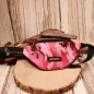 Preview: Vorderansicht der pinken Camouflage-Gürteltasche für Kinder mit Sport-Schriftzug auf einer Holzscheibe.