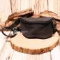 Preview: Vorderansicht der kleinen schwarzen Stoff-Gürteltasche für Kinder auf einer rustikalen Holzscheibe präsentiert.