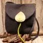 Preview: Flache graue Handtasche aus Filz mit aufgenähter weißer Calla-Blüte, schwarzem Innenfutter und langem Schulterband vor neutralem Hintergrund.