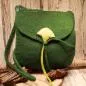 Preview: Flache grüne Handtasche aus Filz mit aufgenähter weißer Calla-Blüte, schwarzem Innenfutter und langem Schulterband vor neutralem Hintergrund.