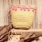 Preview: Kleine runde Korbtasche für Kinder aus naturfarbenem Rattan mit rosa Bommeln, heller Bordüre und Stoff-Innenfutter.