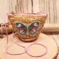 Preview: Kleine runde Korbtasche für Kinder aus naturfarbenem Rattan mit Schmetterlings-Motiv und Kordel-Trageband.