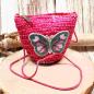 Preview: Kleine runde Korbtasche für Kinder in Pink aus Rattan mit Schmetterlings-Motiv und Kordel-Trageband.