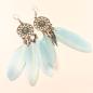 Preview: Lange silberne Traumfänger Ohrringe mit türkisblauem Stein, hellblauen Federn und drei versilberten Metallfedern.