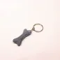 Preview: Handgefertigter Mini Knochen aus blauem Filz als witziger Schlüsselanhänger und weicher Taschenbaumler, hängend und liegend dargestellt.