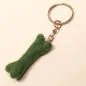 Preview: Handgefertigter Mini Knochen aus grünem Filz als witziger Schlüsselanhänger und weicher Taschenbaumler, Gesamtansicht.