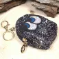 Preview: Schwarzes Glitzer Schlüsselanhänger Mäppchen mit Augen-Motiv, geschlossenem Reißverschluss und silbernem Schlüsselring.
