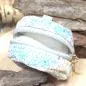 Preview: Nahaufnahme des glitzernden Stoff-Materials der kleinen schwarzen Utensilientasche und des Reißverschlusses.