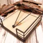 Preview: Quadratischer Serviettenhalter aus schwarzem Metall-Zaun und hellem Holz mit einem Kugel-Gewichtarm auf einer Baumscheibe.