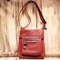 Preview: Rote Leder Handtasche mit Reißverschlussfächern auf der Vorderseite, kompaktes Design und langer, verstellbarer Schultergurt.