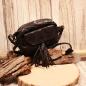 Preview: Kleine schwarze Umhängetasche aus Leder mit zwei dekorativen Quasten am Magnetverschluss und verstellbarem Schulterriemen.