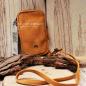 Preview: Braune Leder-Umhängetasche für Damen mit Reißverschluss, kleinem Innenfach und abnehmbarem Schultergurt auf rustikalem Holzgrund.