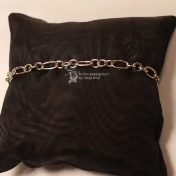 Versilbertes Gliederarmband mit Wechselmuster aus runden und rechteckigen Gliedern auf dunklem Schmuckkissen präsentiert.