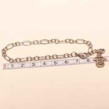 Versilbertes Bettelarmband an einem Maßband zur Veranschaulichung der Länge von 20 cm und 22 cm mit Engel.