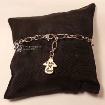 Versilbertes Bettelarmband aus Metall mit Schutzengel-Anhänger Schriftzug made for an Angel auf braunem Schmuckkissen.