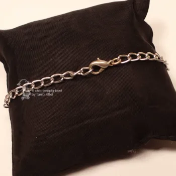Nahaufnahme des geöffneten Karabiner-Verschlusses am leichtgliedrigen Metall-Aluminium-Armband auf schwarzem Kissen.