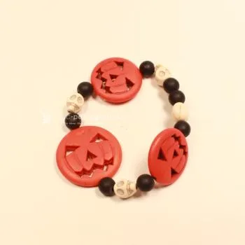 Elastisches Handmade Armband mit großen orangefarbenen Kürbisperlen und kleinen schwarzen Totenkopfperlen im Wechsel.