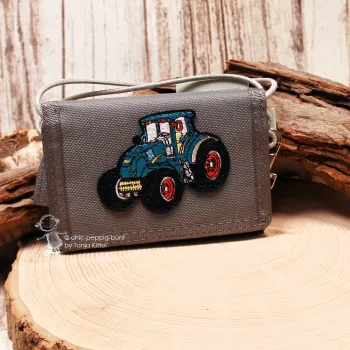 Grauer Kinder-Brustbeutel aus robustem Spinnstoff mit gesticktem, blau-schwarzem Traktor-Motiv und roten Felgen.