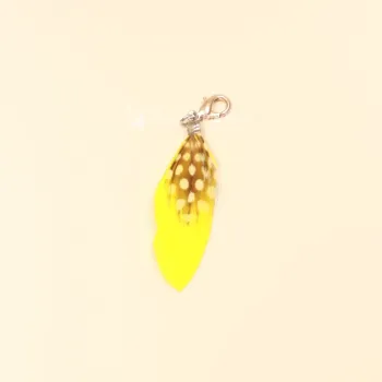 Gelber Charmsanhänger Feder mit weißen Polka Dots und silbernem Karabiner.