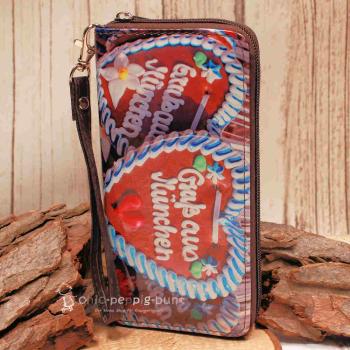 Detailaufnahme der braunen Kunstleder-Handschlaufe mit Karabinerhaken am Portemonnaie.