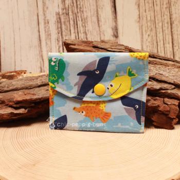 Kleiner handgenähter Geldbeutel von chic-peppig-bunt aus blauem Stoff mit Fisch-Motiv und bunt gestreiftem Innenfutter auf hellem Hintergrund.