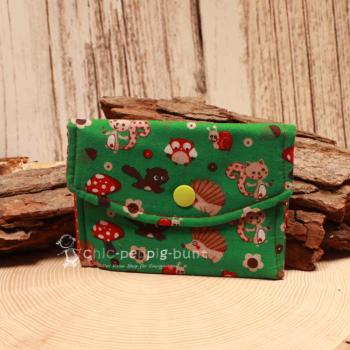 Kleiner handgenähter Geldbeutel von chic-peppig-bunt aus grünem Stoff mit Igel, Pilz und Eichhörnchen sowie rot-weiß gepunktetem Futter.