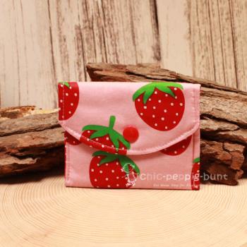 Kleiner handgenähter Geldbeutel von chic-peppig-bunt aus rosa Stoff mit Erdbeeren und rot-weiß gepunktetem Innenfutter auf hellem Hintergrund.