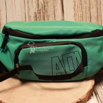 Rückseite der grünen Hüfttasche mit Fokus auf das glatte, abwaschbare Nylon-Material und den Gurt.