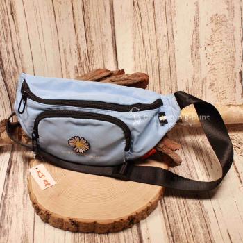 Hellblaue Gürteltasche aus Nylon mit aufgenähter weißer Margeriten-Blume und Reißverschluss.