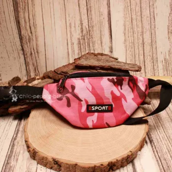 Vorderansicht der pinken Camouflage-Gürteltasche für Kinder mit Sport-Schriftzug auf einer Holzscheibe.
