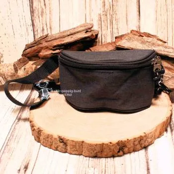 Vorderansicht der kleinen schwarzen Stoff-Gürteltasche für Kinder auf einer rustikalen Holzscheibe präsentiert.