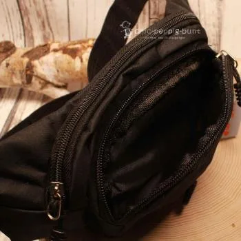 Lässige Trageweise der schwarzen Hip Bag mit Gurtschnalle als Crossbody-Tasche über der Brust.