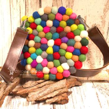 Die runde Filzkugel Handtasche hängt lässig am Lederriemen.