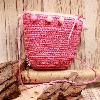 Kleine runde Korbtasche für Kinder in Rosa aus Rattan mit rosa Bommeln und Stoff-Innenfutter.