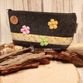 Handgenähte weidräwöl Kosmetiktasche aus grauem Filz mit bunten Punkten und Blumen.