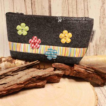 Handgenähte Kosmetiktasche aus dunkelgrauem Filz mit bunten Blumen und gestreiftem Band.