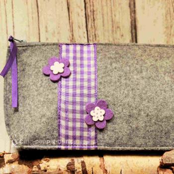 Stabiler Reißverschluss der handgenähten hellgrauen Utensilientasche aus Filz.