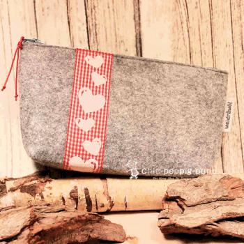 Handgenähte weidräwöl Kosmetiktasche aus hellgrauem Filz mit Herzen und rotem Karoband.