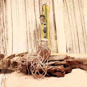 Langes Metall-Lesezeichen mit Ornamenten und großer Textilquaste in Beige.