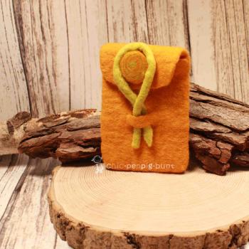 Gelbe handgenähte Utensilientasche aus Filz mit einer leuchtend gelben Gürtelschlaufe für den Hosenbund auf hellem Hintergrund.