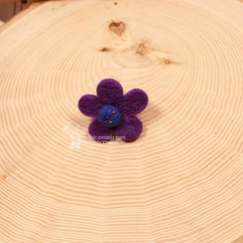 Handgefertigter lila-blauer Filzring für Kinder in Blumenform mit bunt bestickter Perlenmitte auf verstellbarer Schiene.