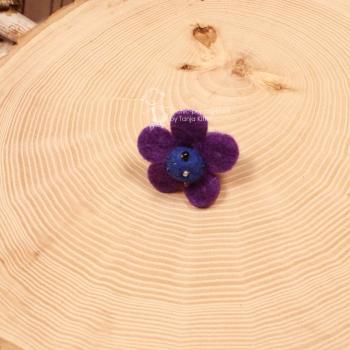 Handgefertigter lila-blauer Filzring für Kinder in Blumenform mit bunt bestickter Perlenmitte auf verstellbarer Schiene.