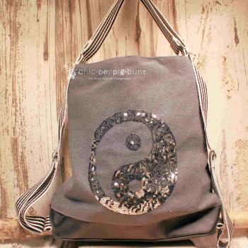 Grauer Rucksack aus Stoff mit silbernem Ying & Yang Symbol aus Pailletten, Lederboden und gestreiften Gurten, 3-in-1 Funktion als Handtasche.