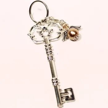 Detailaufnahme Schlüsselanhänger goldener Vintage-Schlüssel mit abnehmbarem Engel-Charm und Strass auf Holzgrund – Handgefertigt von chic-peppig-bunt Deutschland.