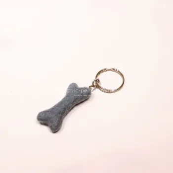 Handgefertigter Mini Knochen aus blauem Filz als witziger Schlüsselanhänger und weicher Taschenbaumler, hängend und liegend dargestellt.