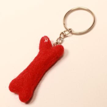 Handgefertigter Mini Knochen aus rotem Filz als witziger Schlüsselanhänger und weicher Taschenbaumler, Gesamtansicht.