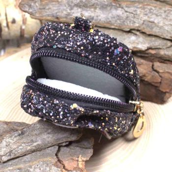 Nahaufnahme des glitzernden Stoff-Materials der kleinen schwarzen Utensilientasche und des Reißverschlusses.
