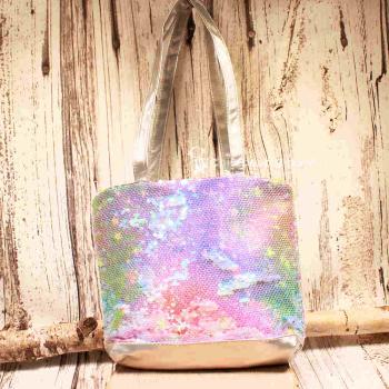 Kleine lila-blau schimmernde Kindertasche mit Pailletten-Stickerei, silbernem Boden und grauen Kunstleder-Griffen auf rustikalem Holzgrund.
